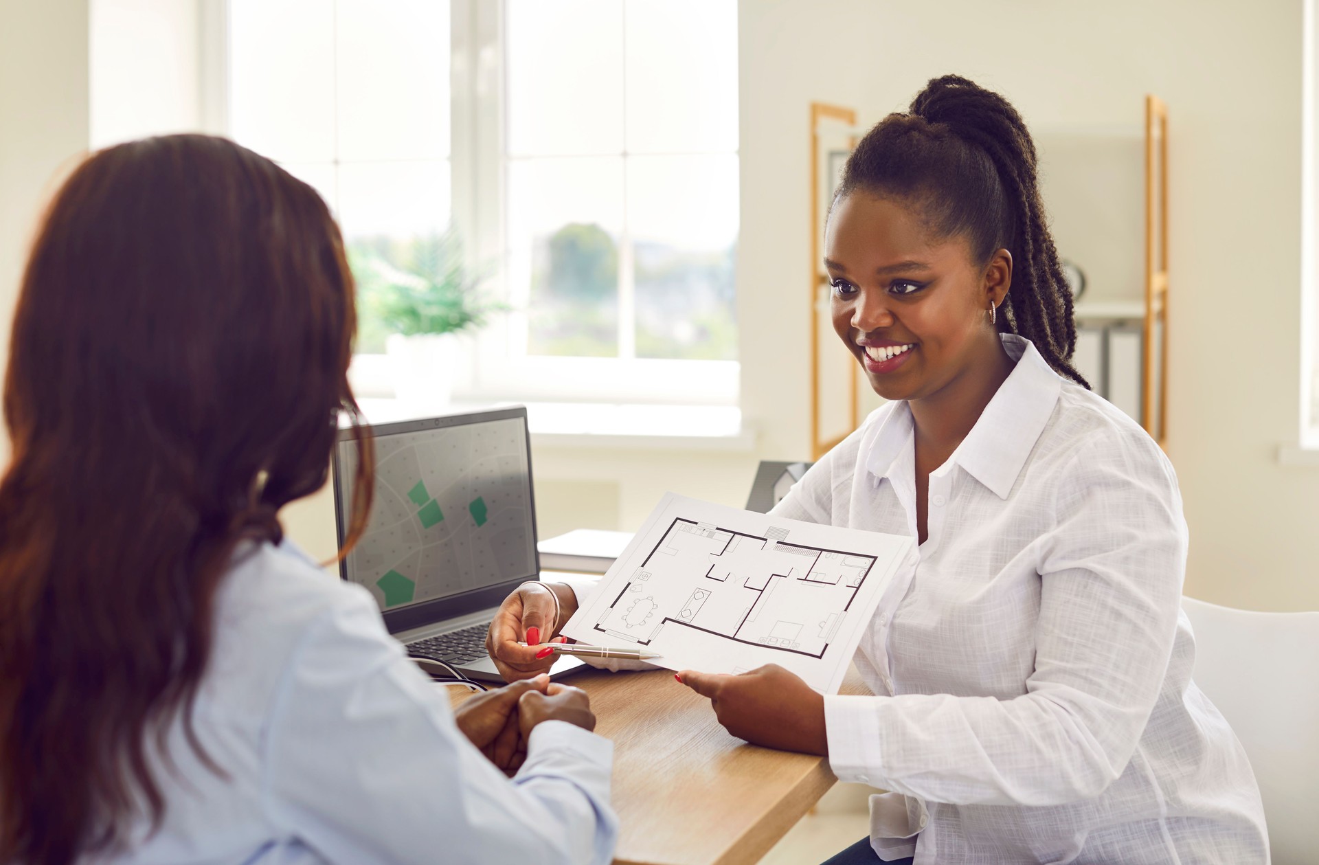 Femme sympathique agent immobilier ou agent immobilier montrant des plans d’étage à son client